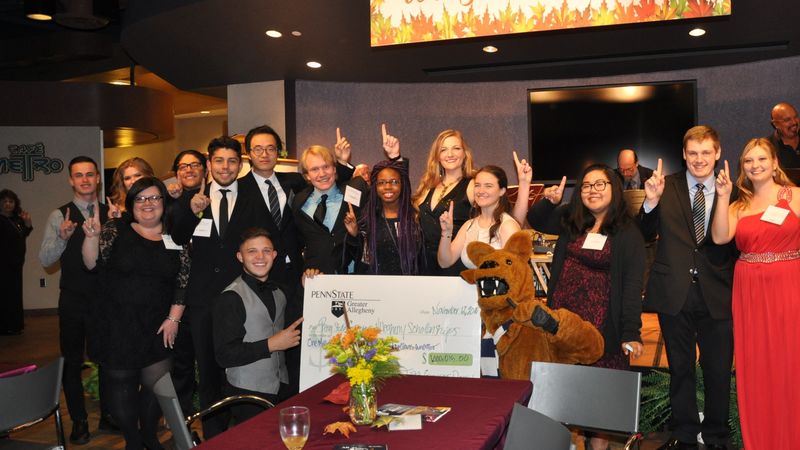students dressed up holding big check students dressed up holding big check