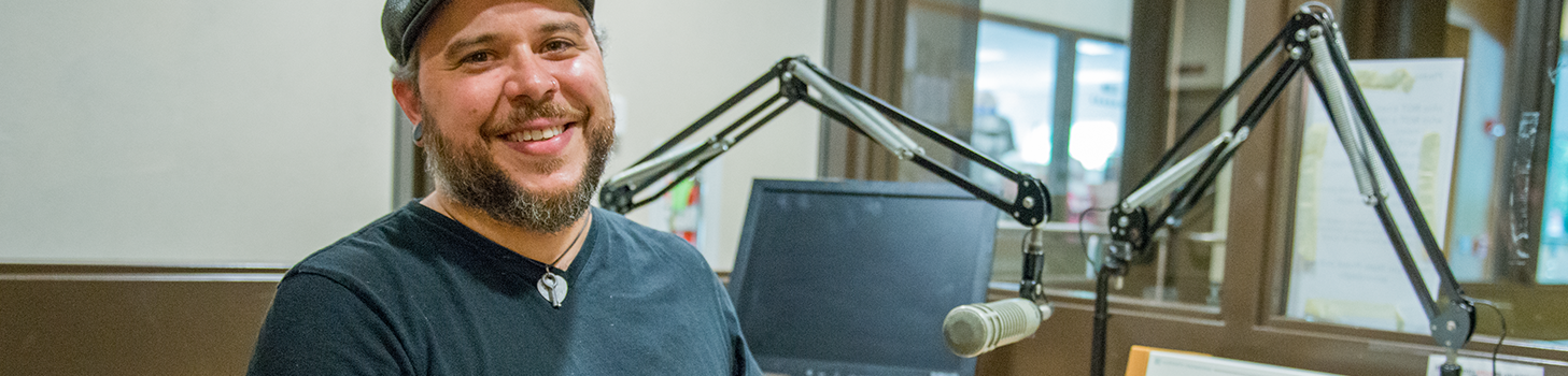 Dr. Zack Furness in the campus radio station smiling 