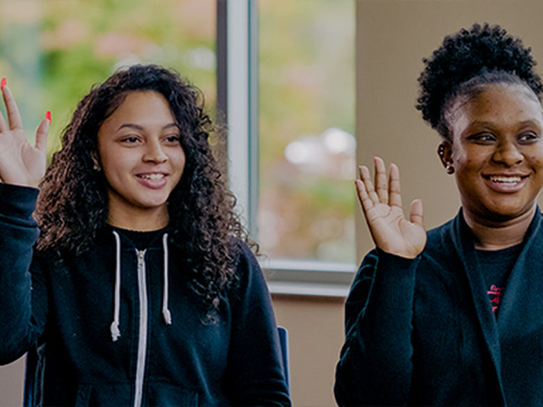 two students raising their hands. 