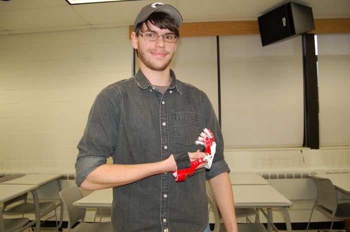 male student holding prosthetic hand