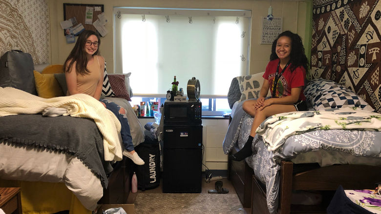 two students sitting on their beds in their dorm room 