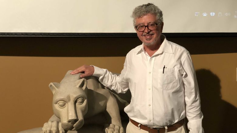Teaching International Speaker Dr. Winter standing next to a replica Lion Shrine