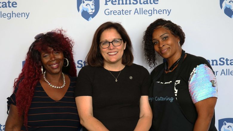 3 women smiling standing in front of Penn State Greater Allegheny Logo
