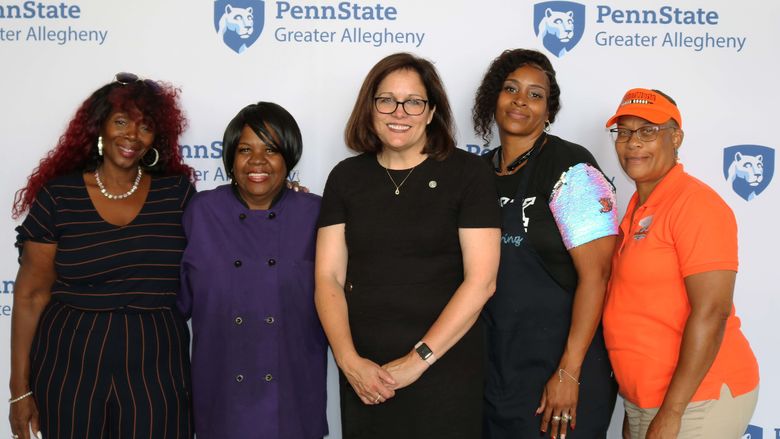 a group of women smiling, standing in front of Penn State Greater Allegheny Mark 