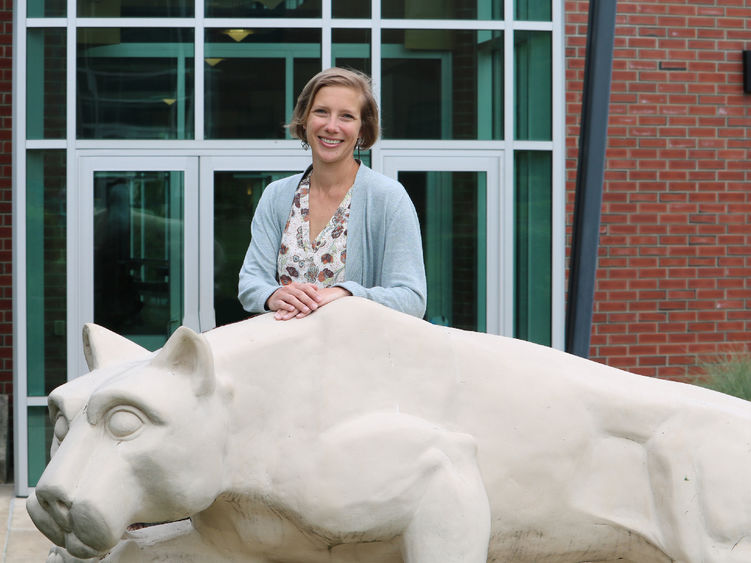 Megan Nagel stands smiling behind the Nittany Lion statue at Penn State Greater Allegheny.