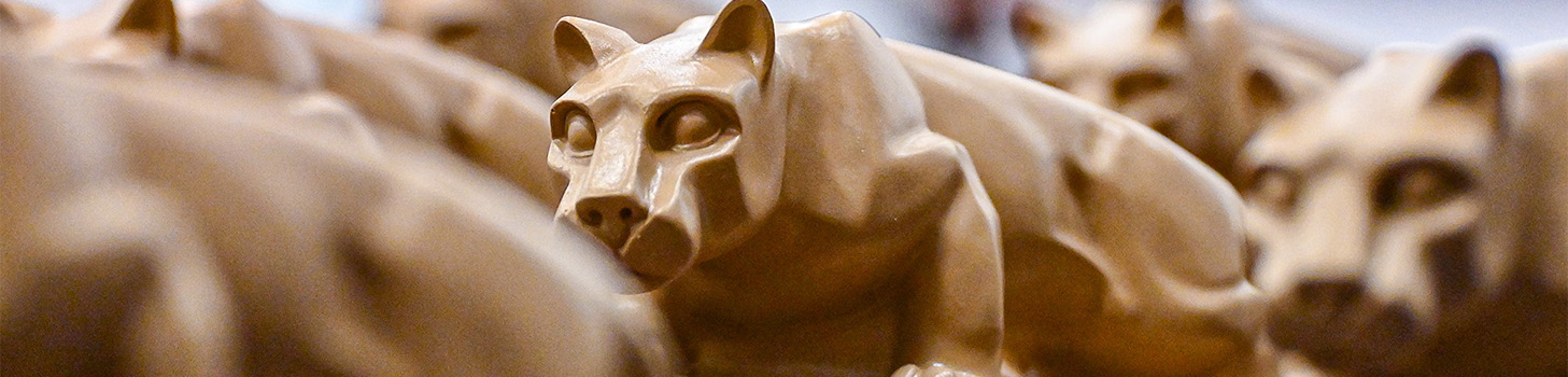 Image of Nittany Lion Shrine statues grouped together on an awards table at a commencement ceremony.