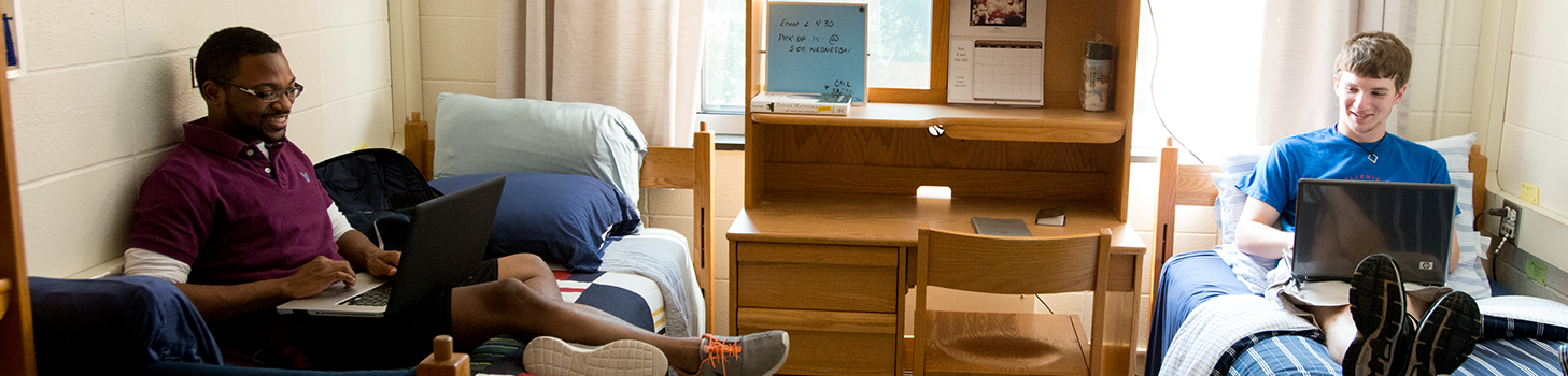Two students sitting on their beds in their dorm room