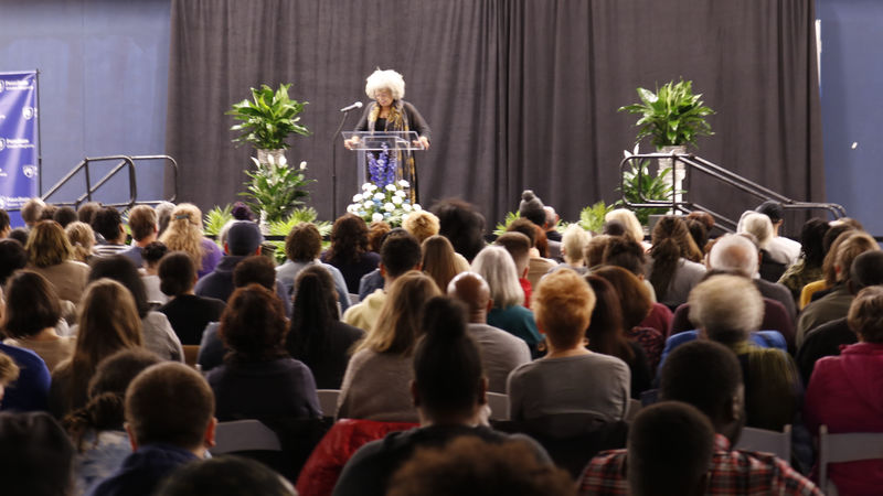 Dr. Angela Davis standing on stage preparing to talk to a crowd of people. 