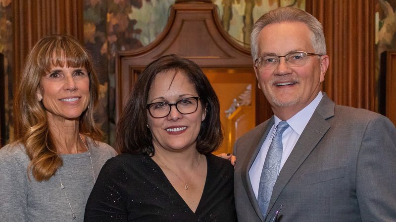 two women and a man smiling at a camera