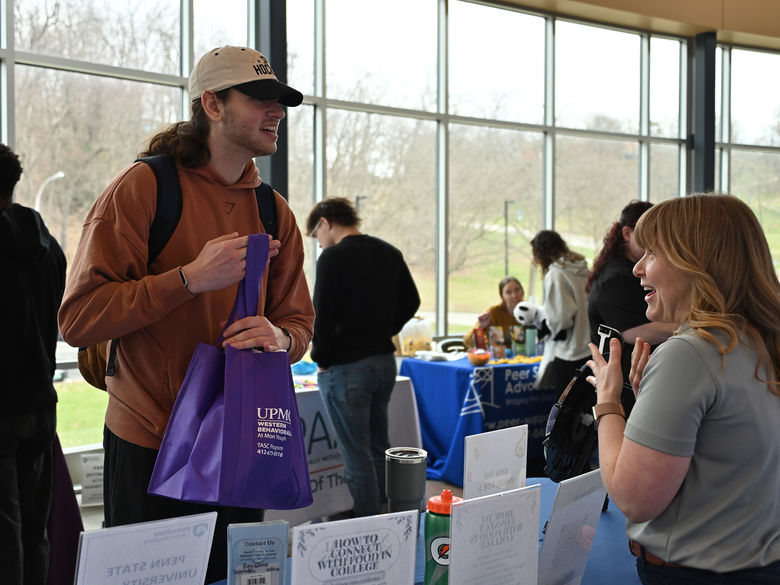 Student holding a purple bag talking to a recruiter