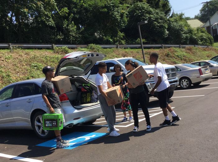 people moving boxes near cars
