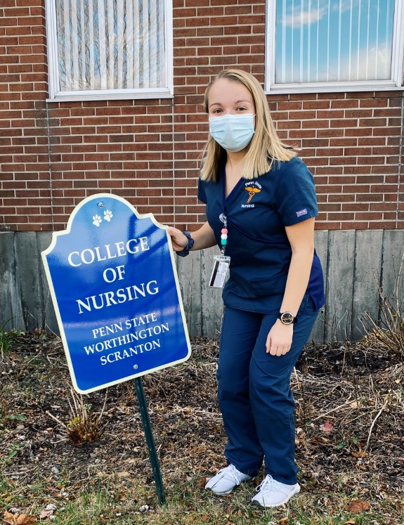 Logan DeSanto posing in front of College of Nursing sign