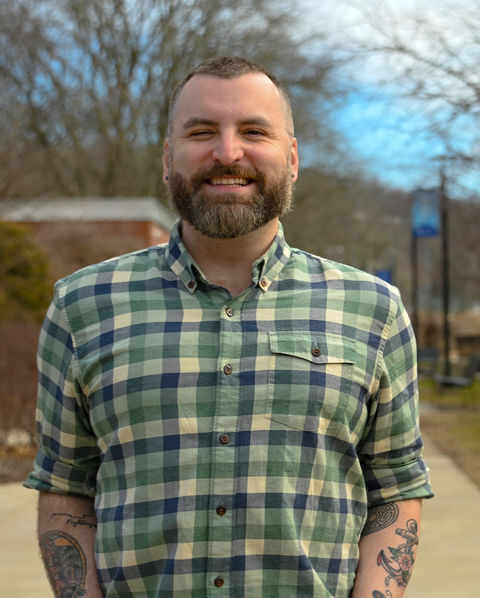 Image of a man smiling wearing a green flannel shirt outside