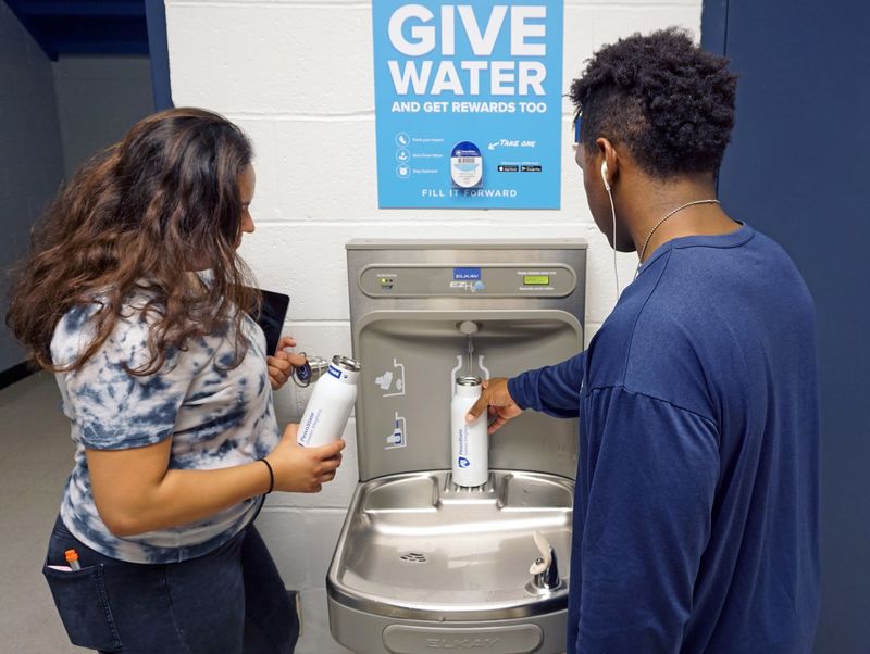 Two student refilling their white water bottles 