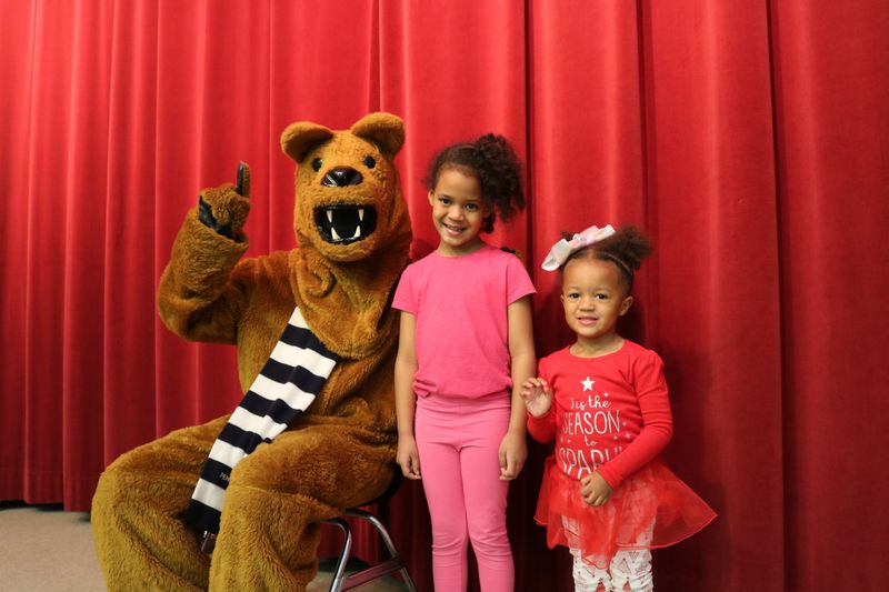 Two Children standing next to the Penn State Nittany Lion Mascot. 