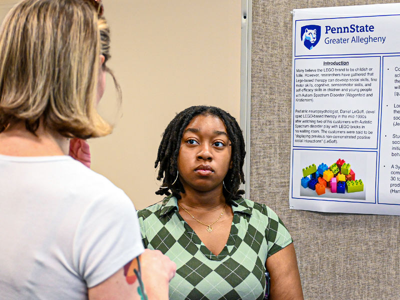 person standing by a research poster, listening to questions