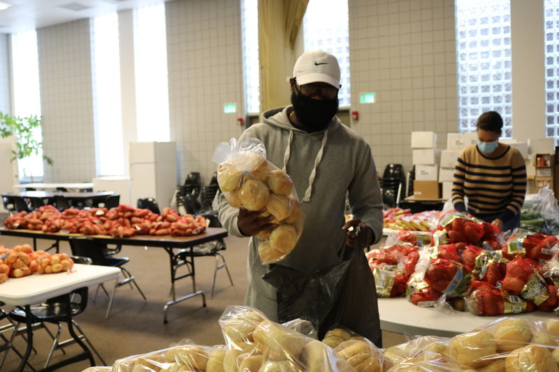 Man holding a package of rolls, preparing to place them into a plastic bag.