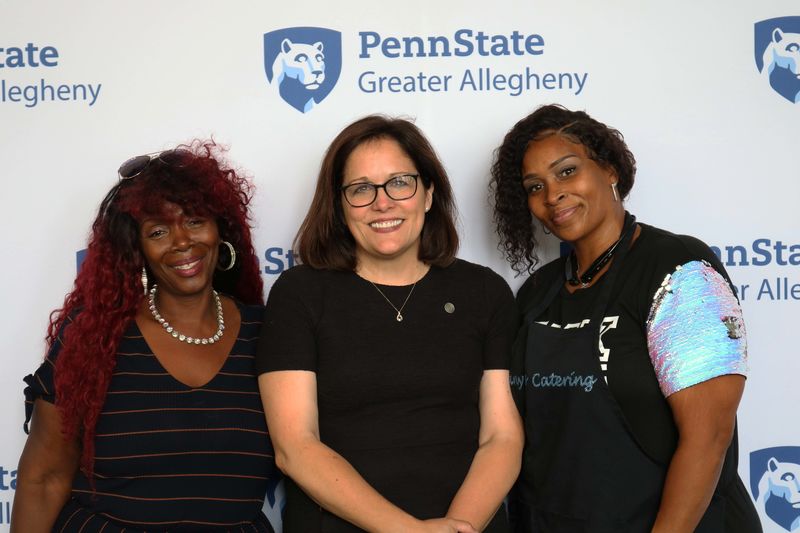 3 women smiling standing in front of Penn State Greater Allegheny Logo