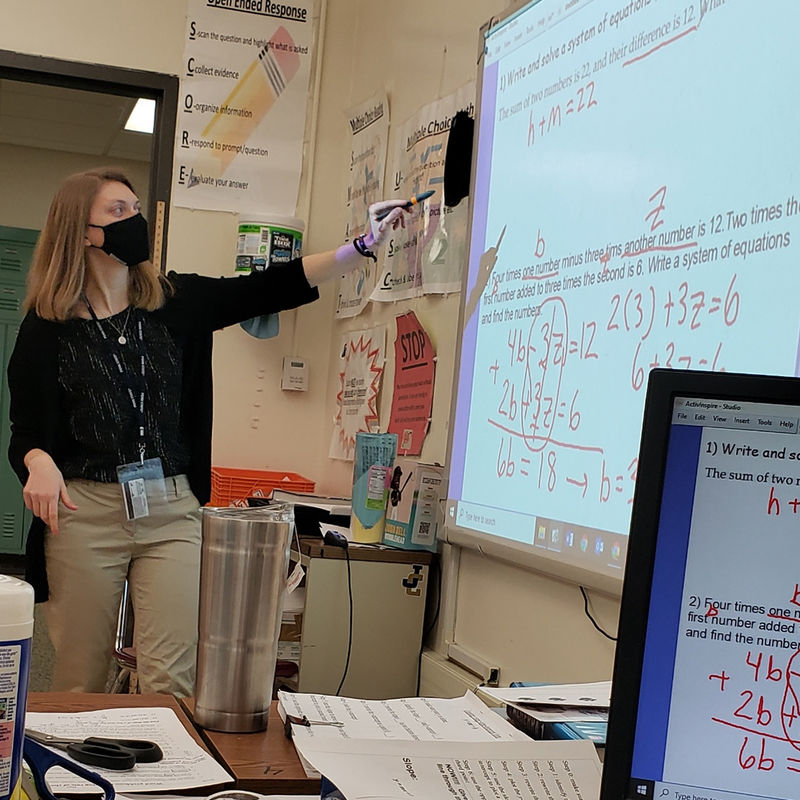 Student Teacher pointing to math assignment on projector screen.