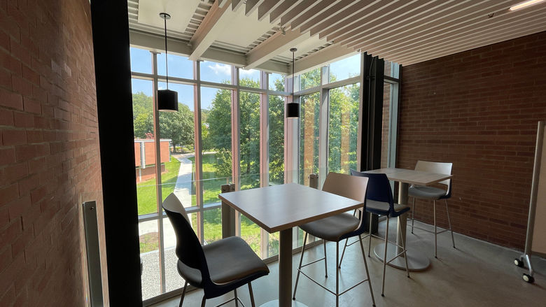 Table and Chairs that sit in front of glass wall that overlooks the campus.