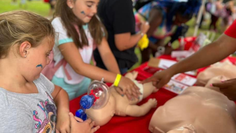 Children practicing CPR on a baby doll