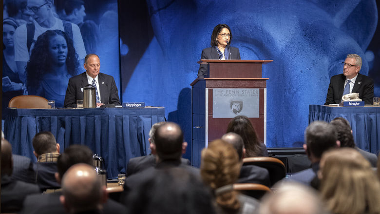 Bendapudi at podium on stage flanked by two trustees