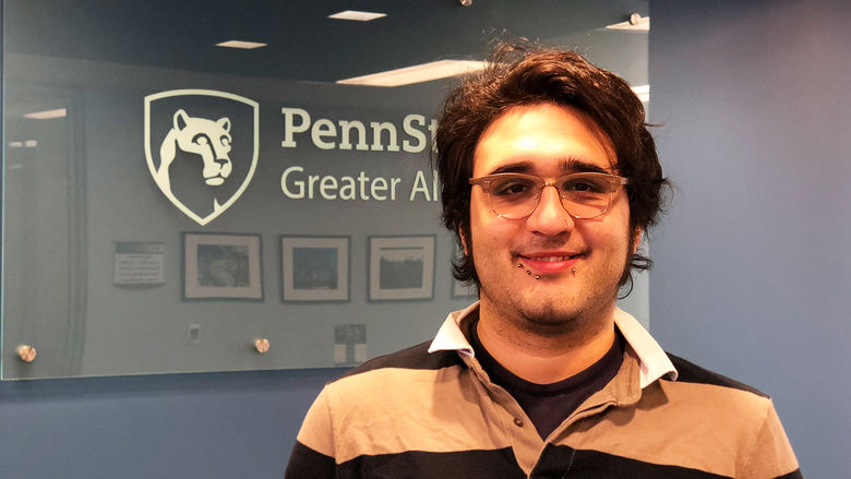 Christian L. Villanueva smiles in front of Penn State Greater Allegheny Logo