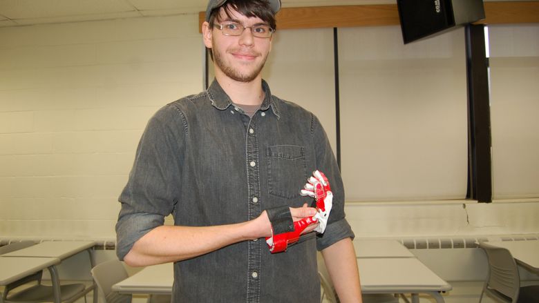 male student holding prosthetic hand