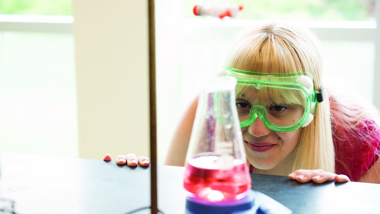 Girl examining beaker filled half way with red liquid