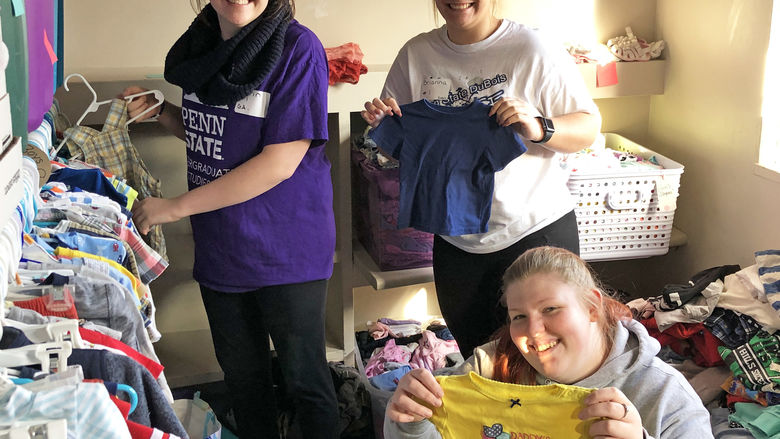 Three students holding up clothing 