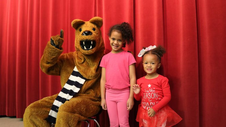 Two Children standing next to the Penn State Nittany Lion Mascot. 