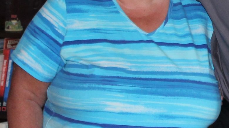 Photo of Colin's mother smiling wearing a multi colored strip shirt 