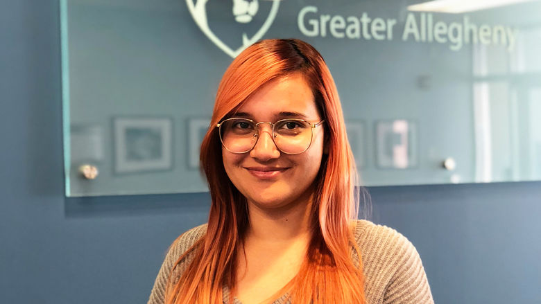 Student Yadeiliz Mari smiling standing in front of Penn State Greater Allegheny Logo