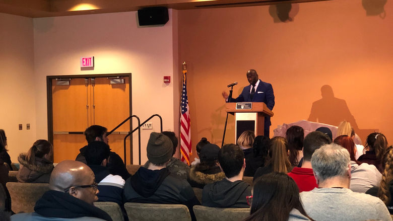man speaking at podium in front of audience