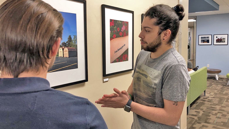 Two students looking at a photograph hanging on a wall in a gallery.