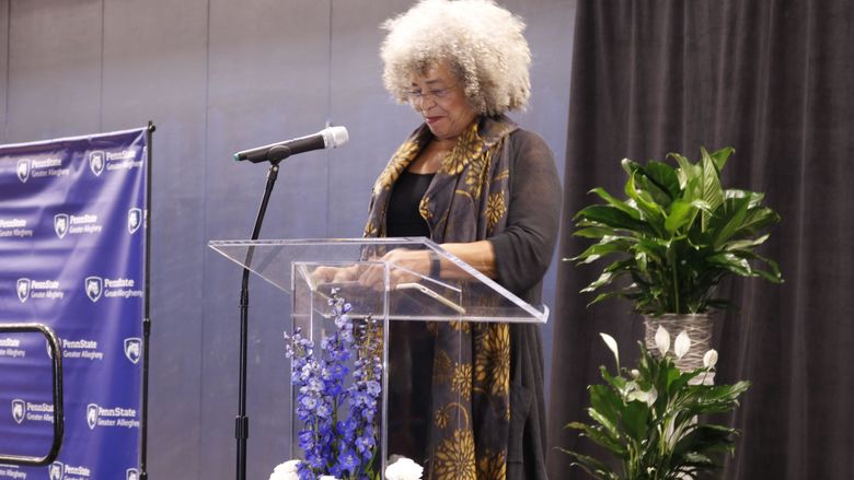 Dr. Angela Davis standing behind clear podium talking into microphone on stand 