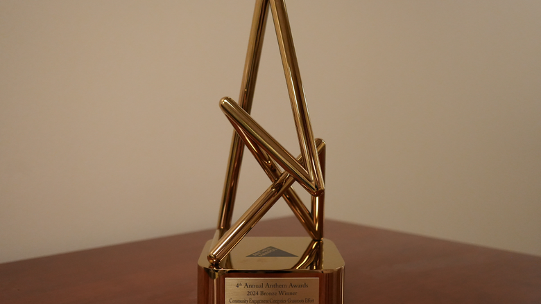 A bronze anthem award on a table, the words "4th Annual Anthem Awards 2024 Bronze Winner; Community Engagement Categories-Grassroots Effort; Rosemary Martinelli, PSU; Paul Ruggieri, GV Media, LLC" are engraved upon its base.