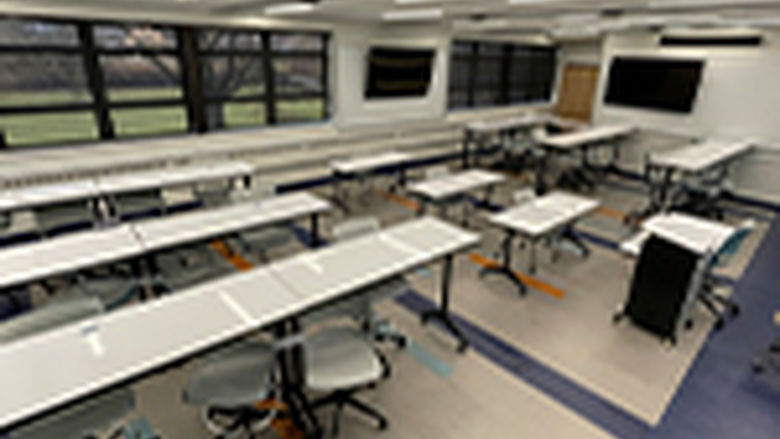 Newly renovated classroom with table, chairs, tv monitors and a podium 