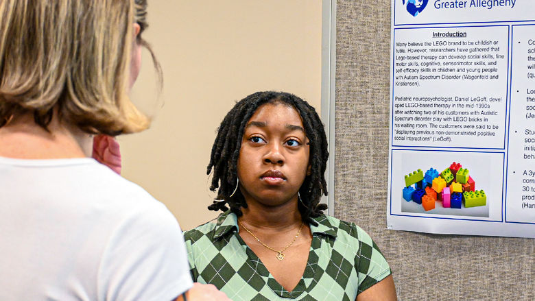 person standing by a research poster, listening to questions