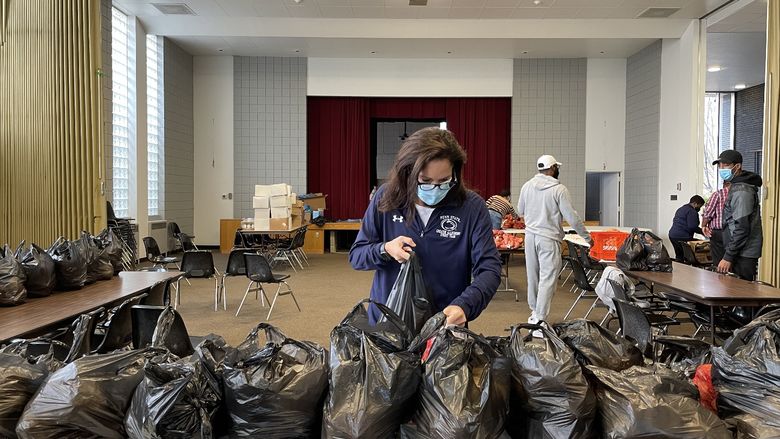 Woman placing a plastic bag on a table filled with other plastic bags.