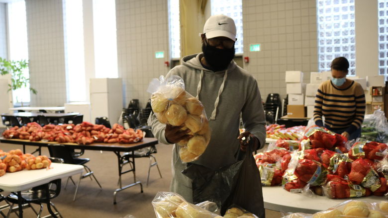 Man holding a package of rolls, preparing to place them into a plastic bag.