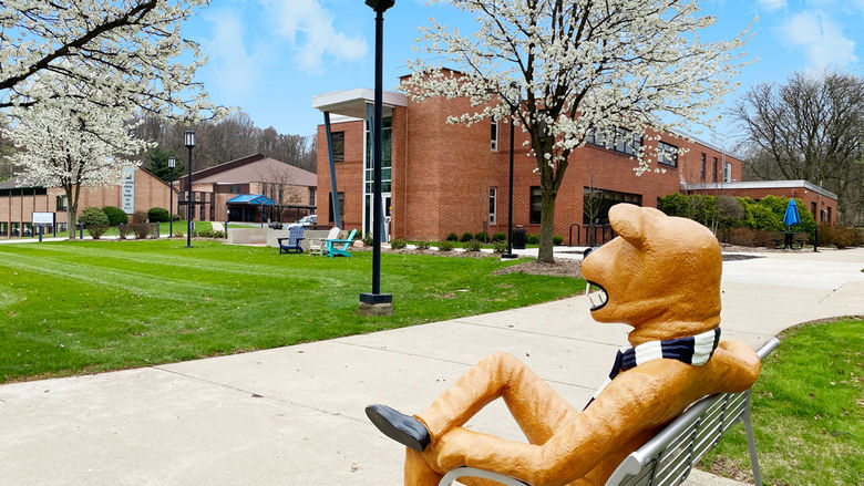 Nittany Lion sitting on a bench outside the Buck Family Lawn at Penn State Greater Allegheny
