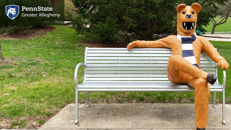 Outdoor bench with mascot sitting on it. 
