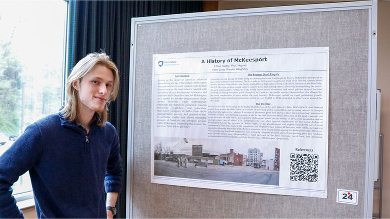Student smiling next to poster