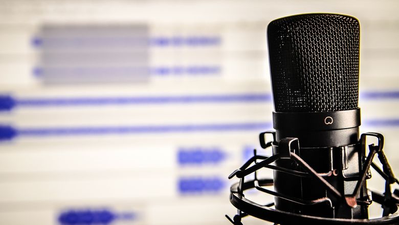 A microphone rests in front of a blurred, white computer screen