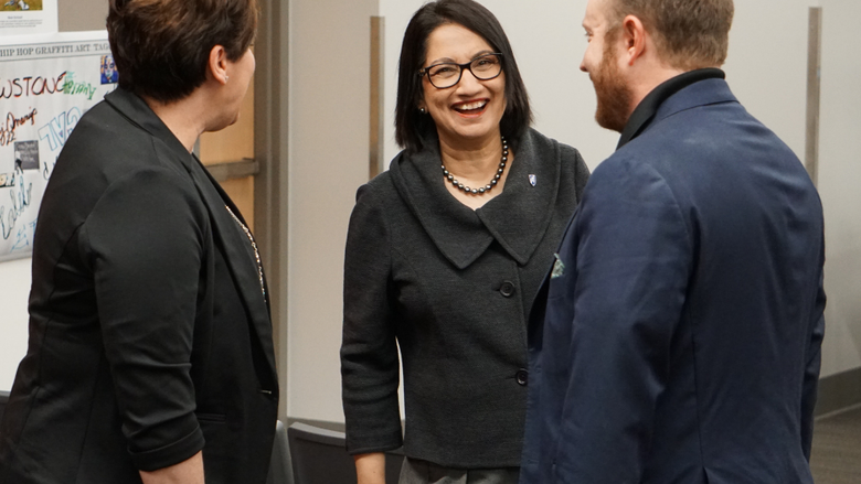 Woman laughing and smiling while standing beside a man and woman.