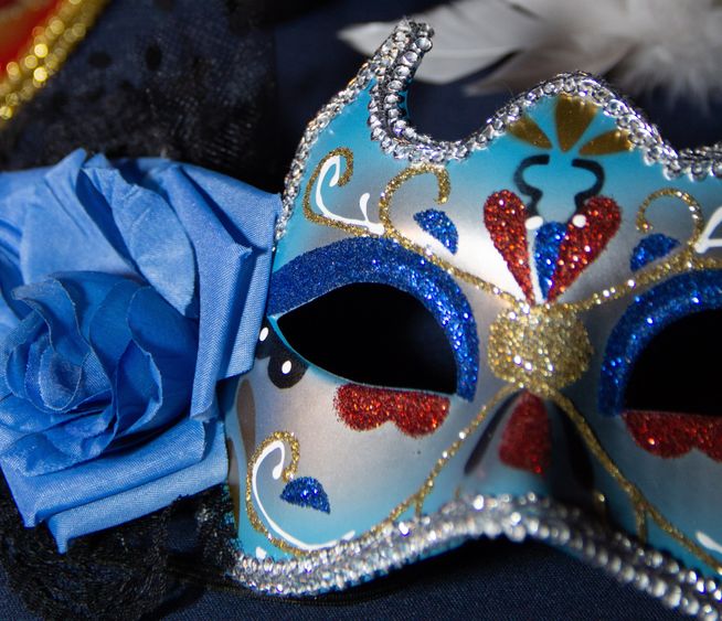Masquerade mask sitting next to rose