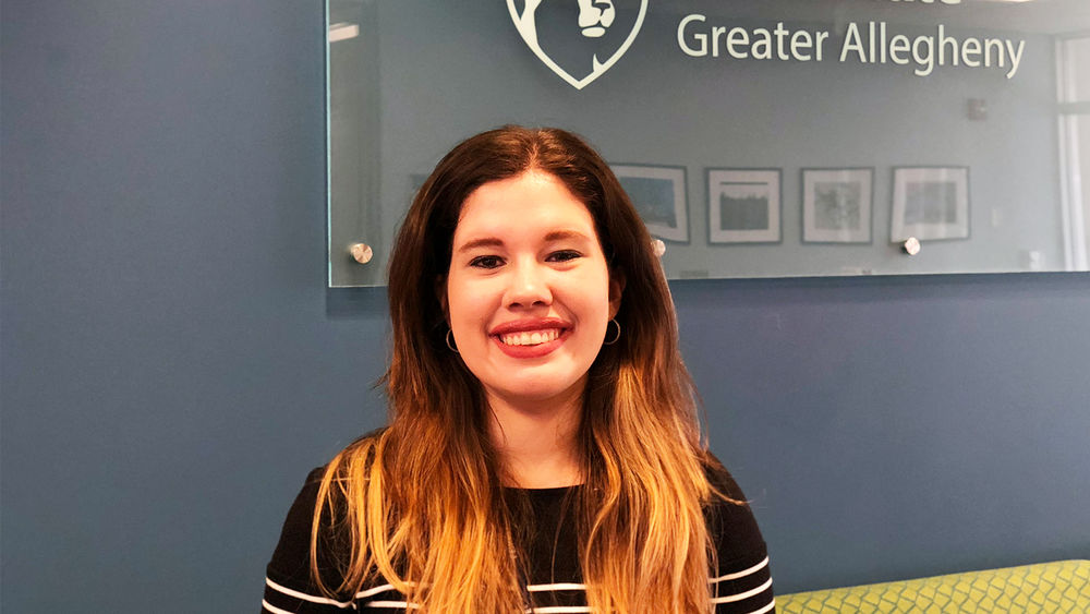 Exchange student Cristina Rivera in front of the Penn State Greater Allegheny Logo. 