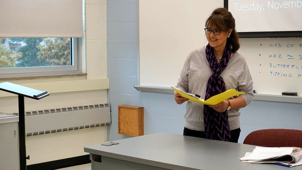 Woman smiling holding book behind a desk.