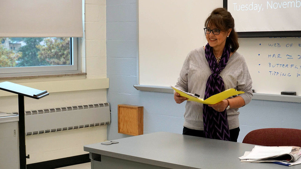 Woman smiling holding book behind a desk. 